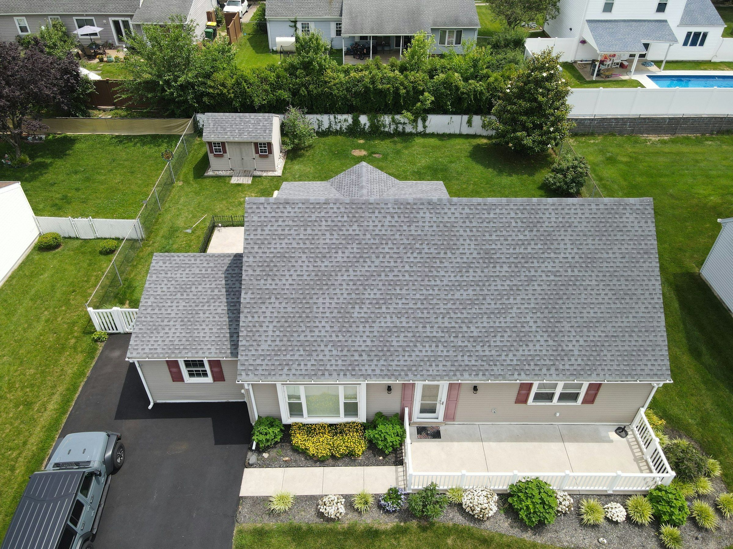 Aerial view of a ranch home with a gray shingle roof