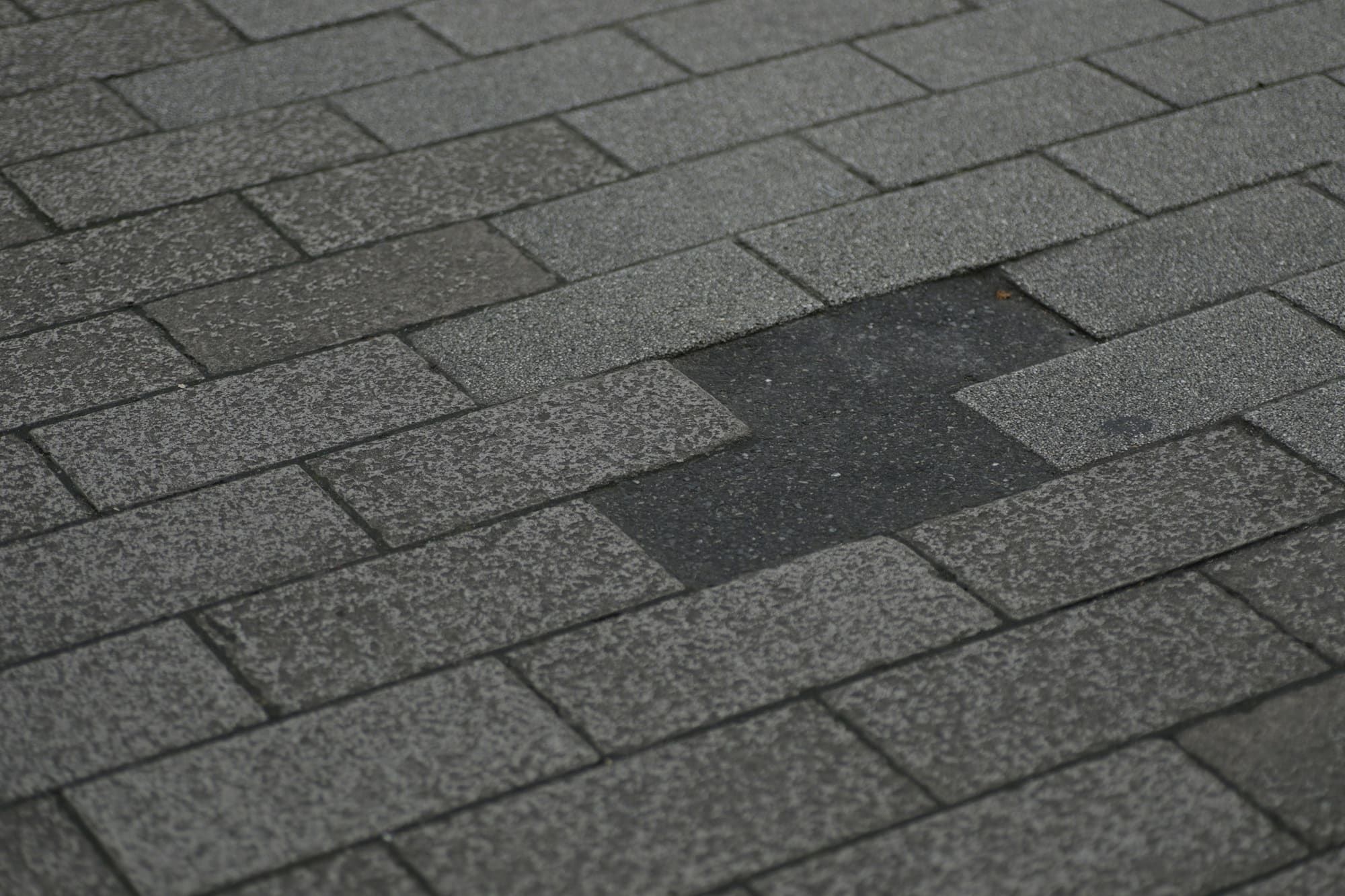 Asphalt shingle roof with a missing shingle tab exposing the layer underneath