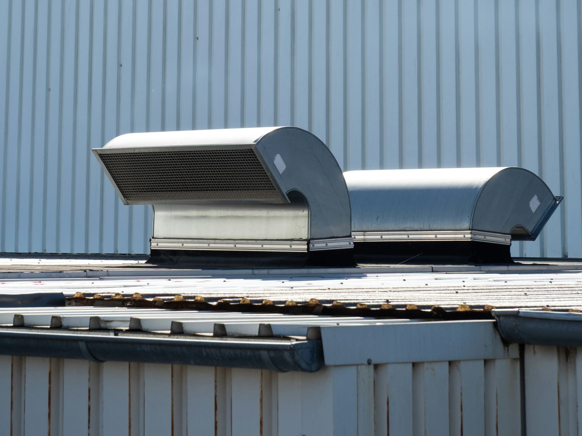 Two ventilation hoods on the roof of a metal-sided building