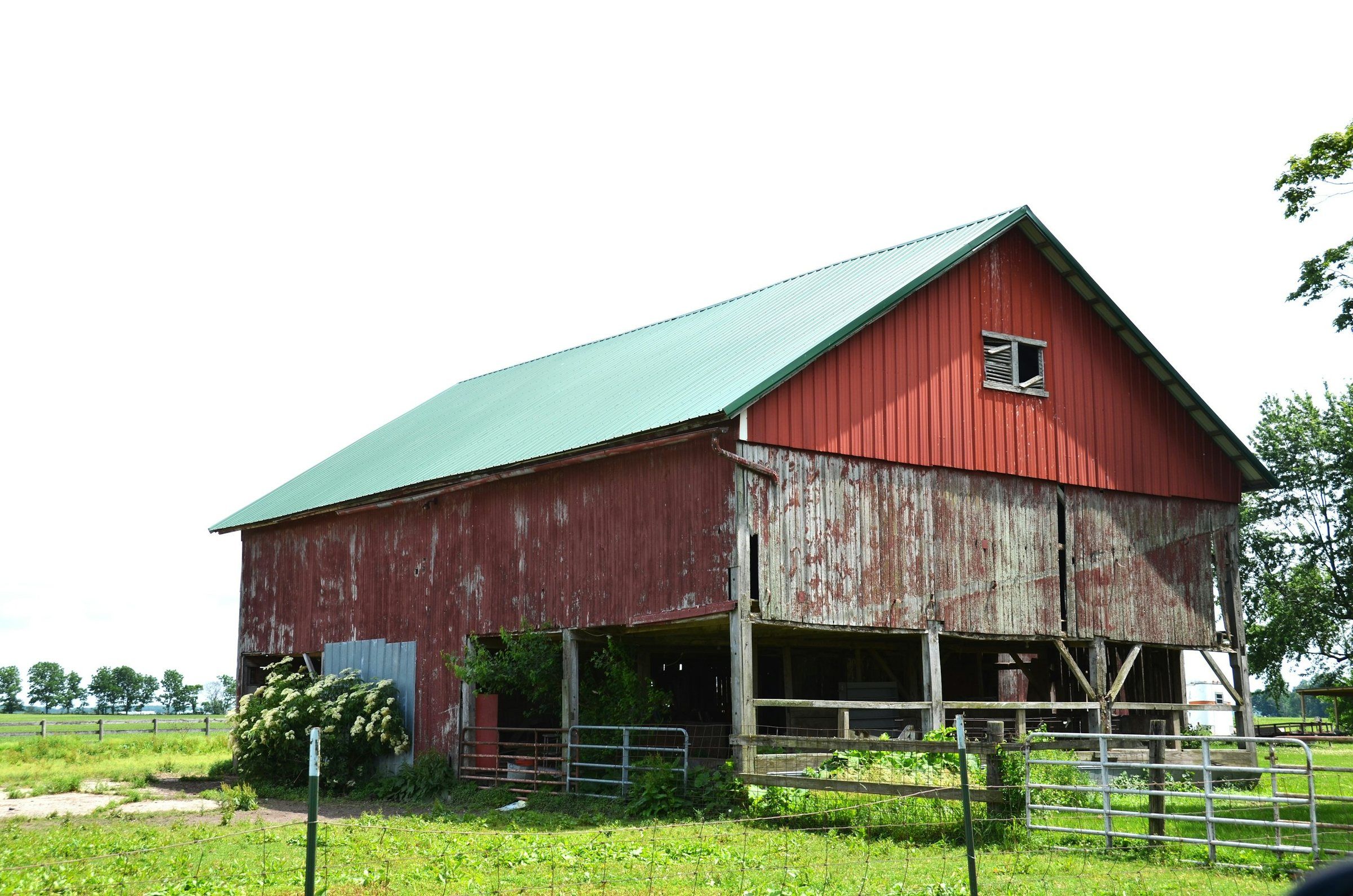 Weathered red barn with a green ribbed steel roof
