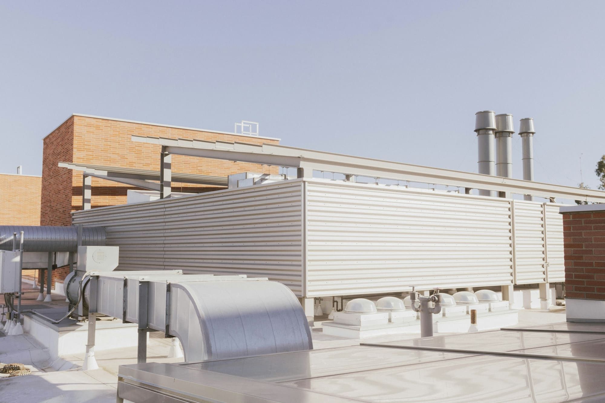 Ductwork, exhaust stacks and a screened mechanical enclosure on a flat commercial roof