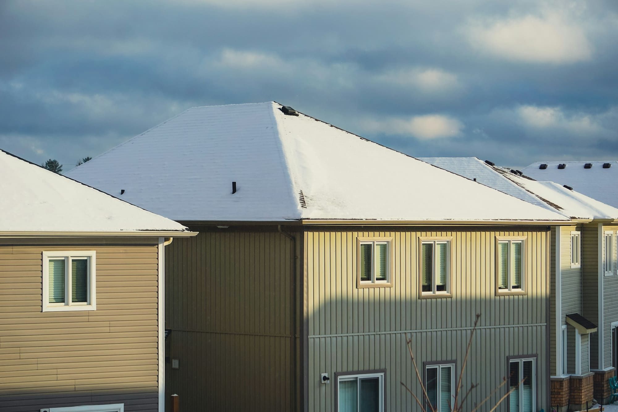 Row of houses with snow-covered roofs under a cloudy sky